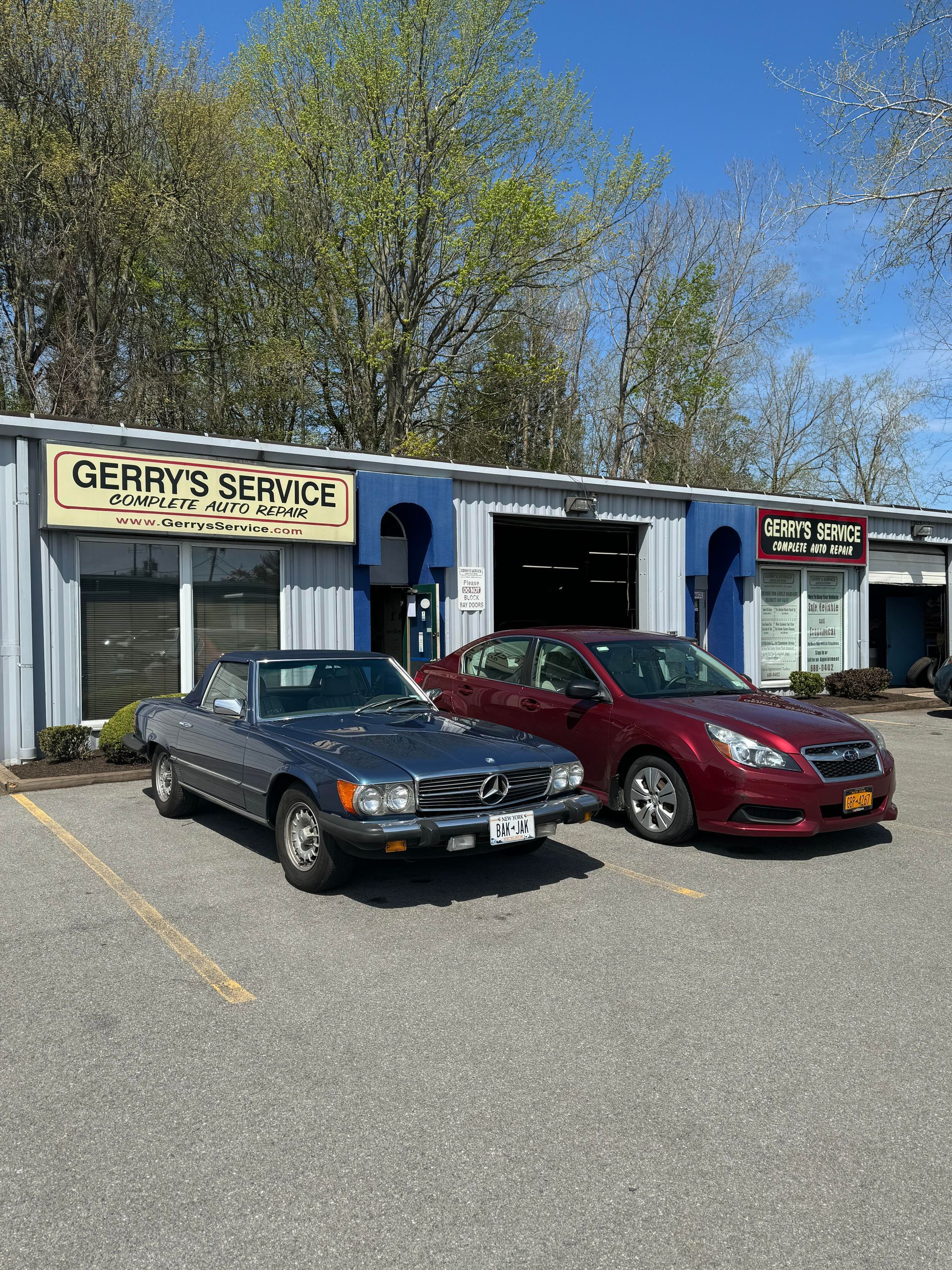 A classic blue car and red sedan parked outside 