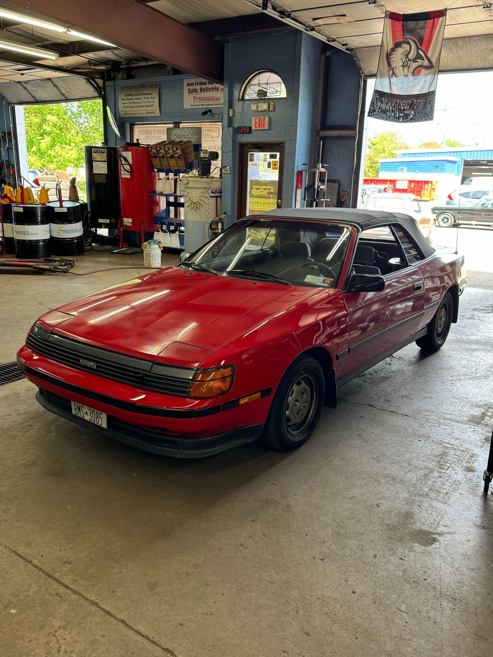 Red Toyota Celica convertible in a car repair shop.