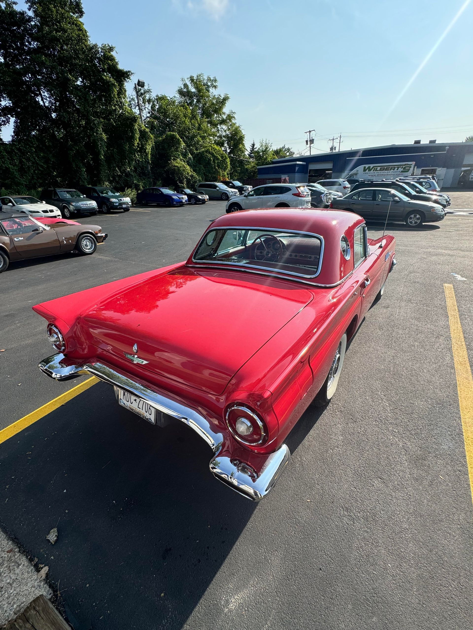 Red classic Ford Thunderbird parked in a lot.