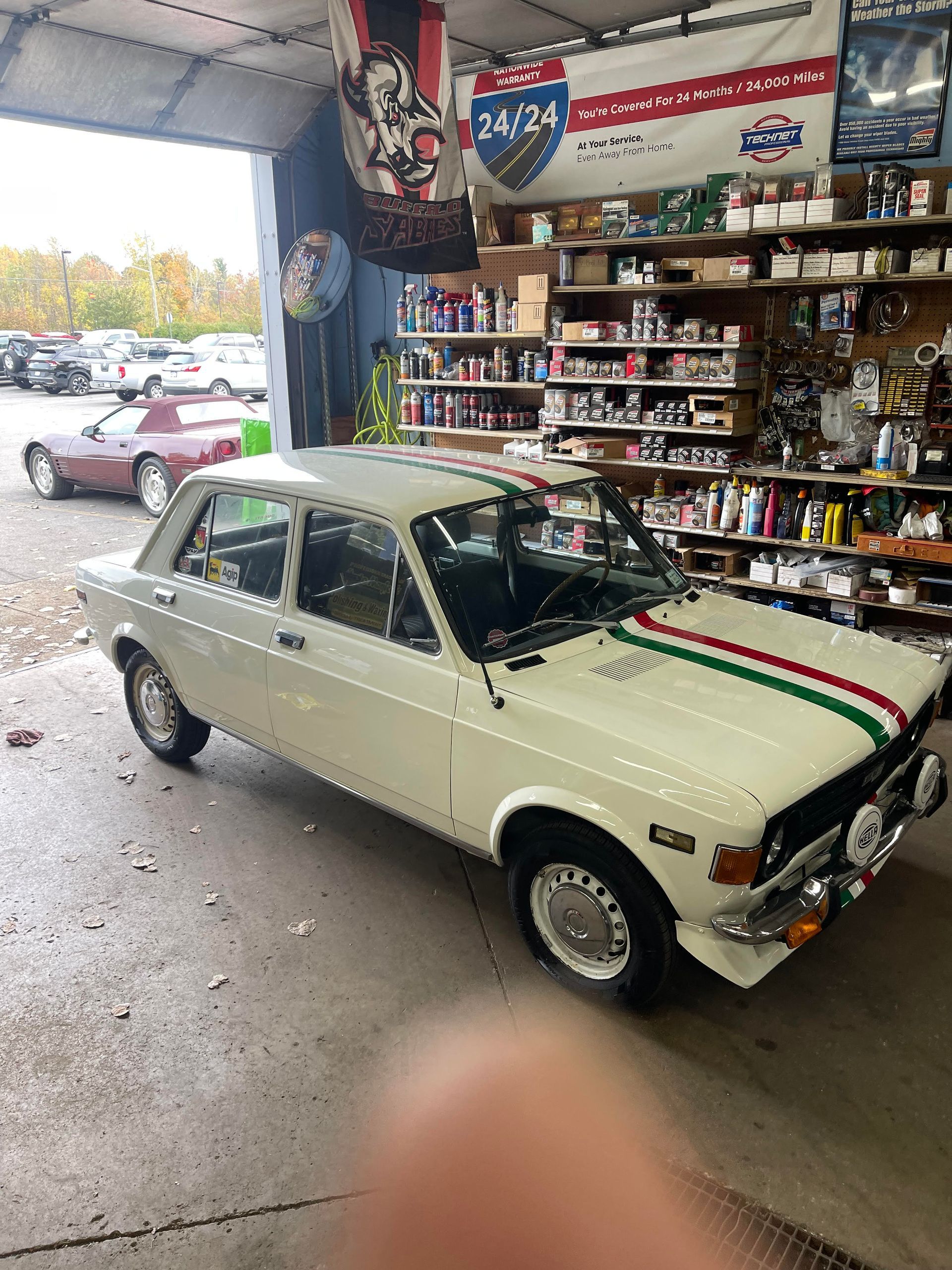 White classic car with Italian flag stripes parked in a garage.
