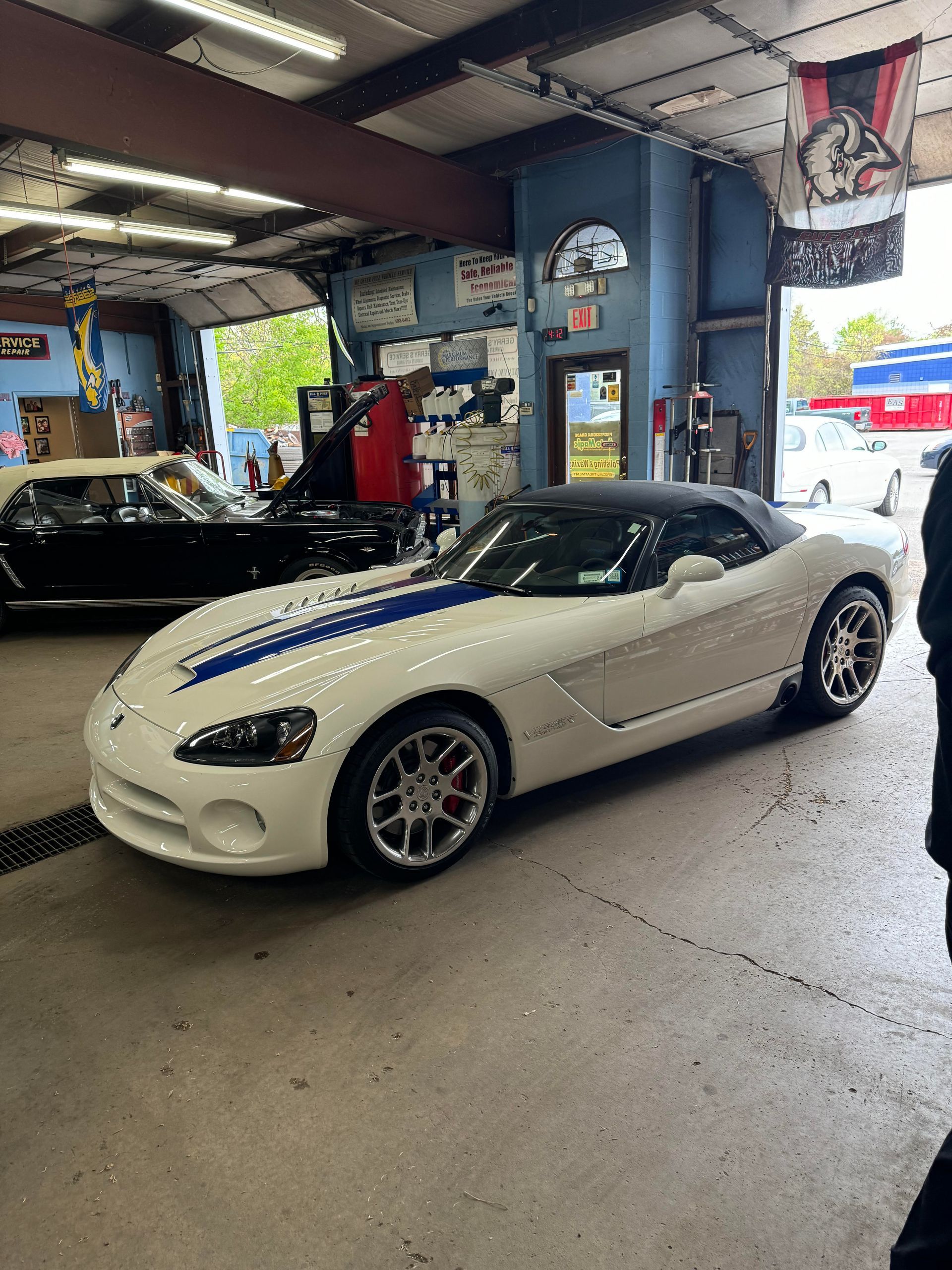 White Dodge Viper convertible with blue stripes inside a garage.