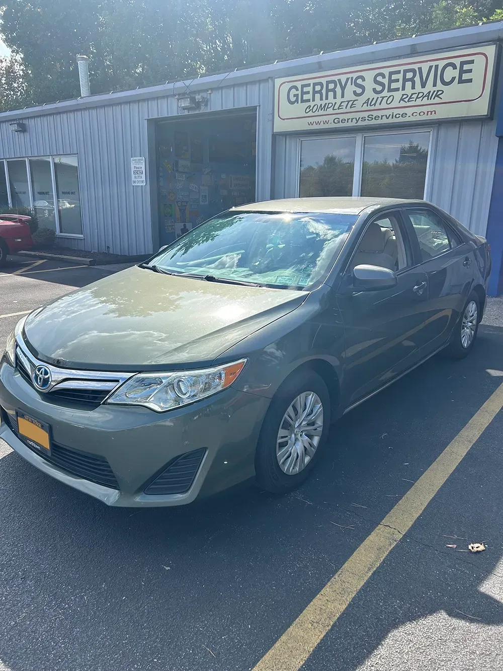 Green Toyota Camry parked in front of a garage,