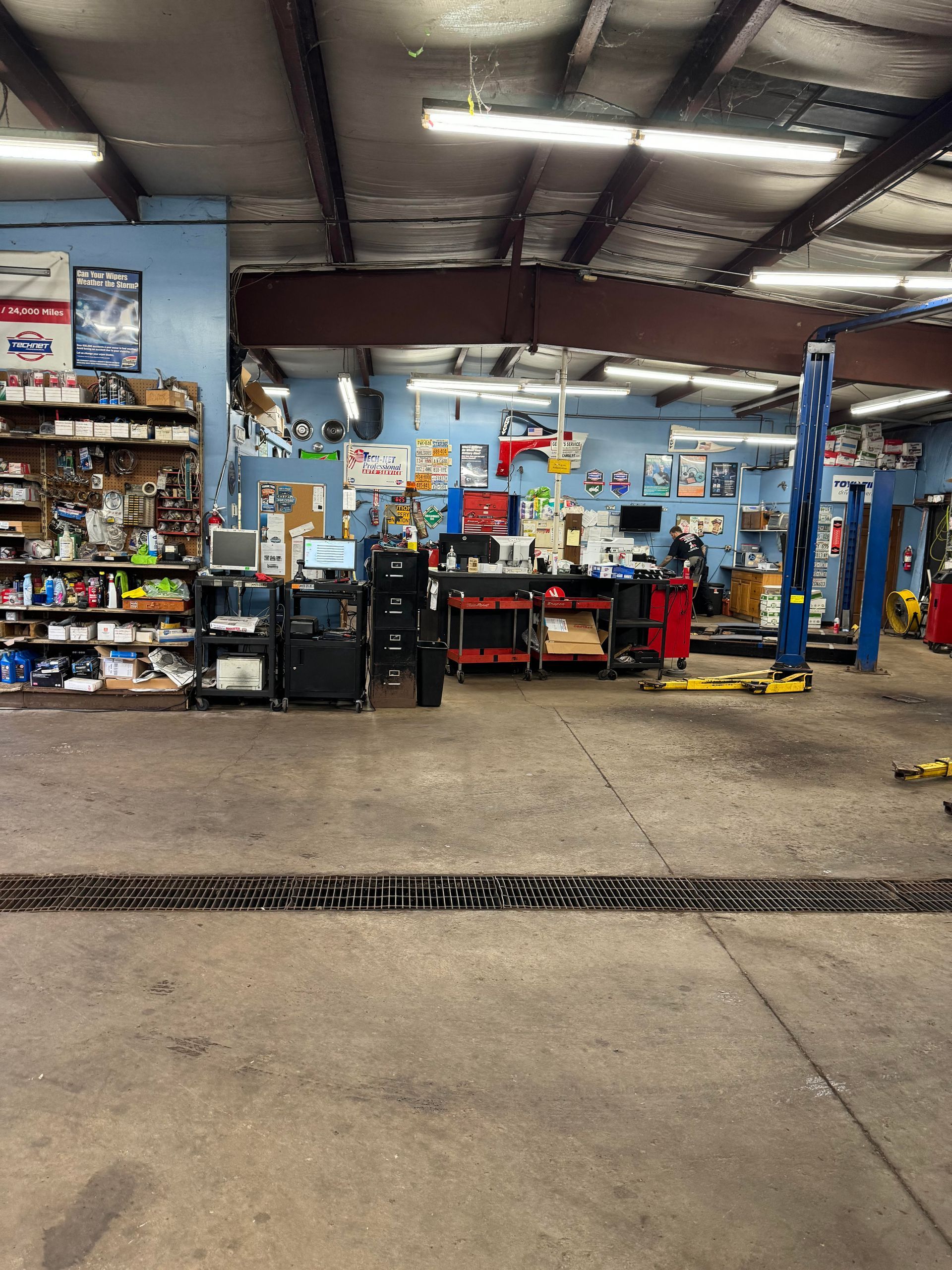 Interior of a garage; tools and equipment. Blue walls, concrete floor, overhead lighting.