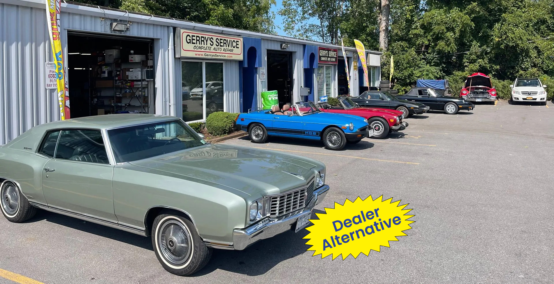 Classic cars parked outside a repair shop, including a light green coupe. Sign says 