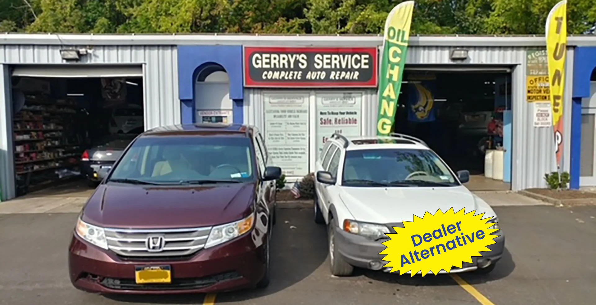 Two cars parked in front of a blue auto repair shop called Gerry's Service.