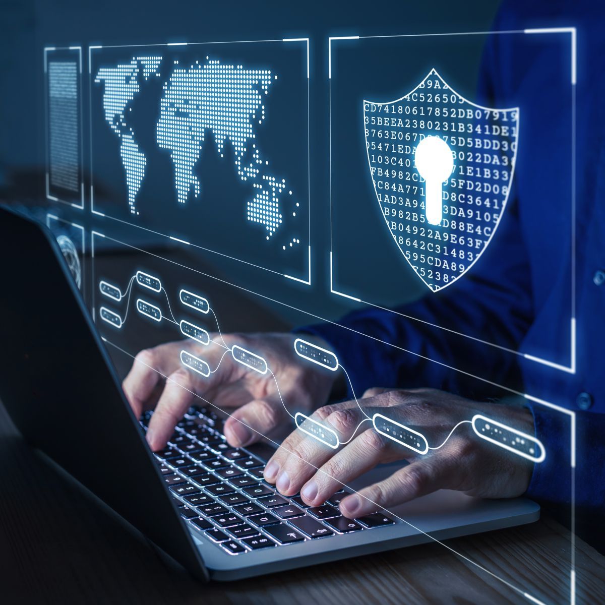 A person is typing on a laptop with a shield on the screen