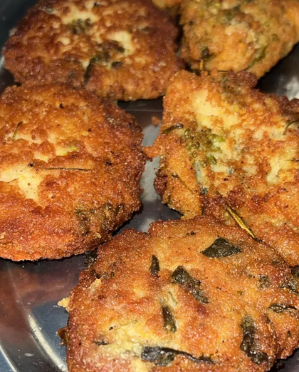 Frittelle dorate e croccanti con pezzetti di erbe aromatiche, servite su un piatto.