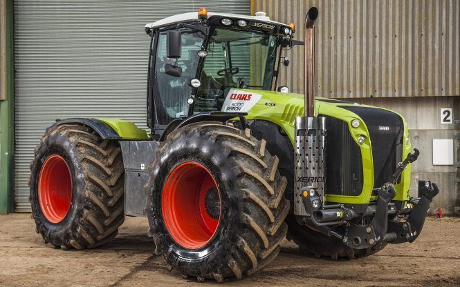 A large tractor with red tires is parked in front of a building.
