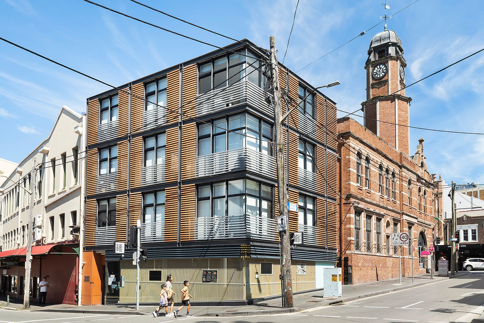 A large building with a clock tower on top of it is on the corner of a city street.
