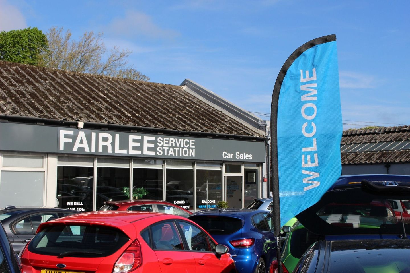 A group of cars are parked in front of a car dealership.