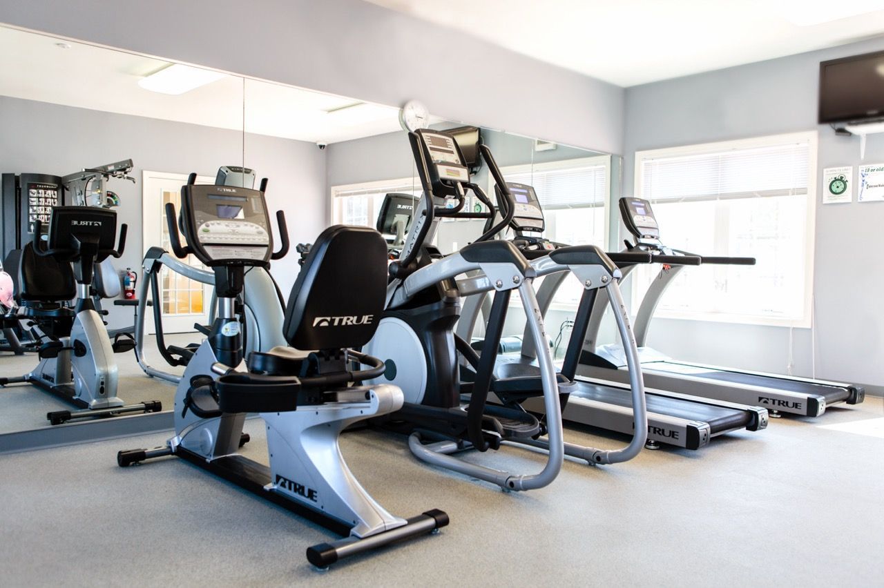 Fitness center with treadmills and ellipticals in a communal gym.