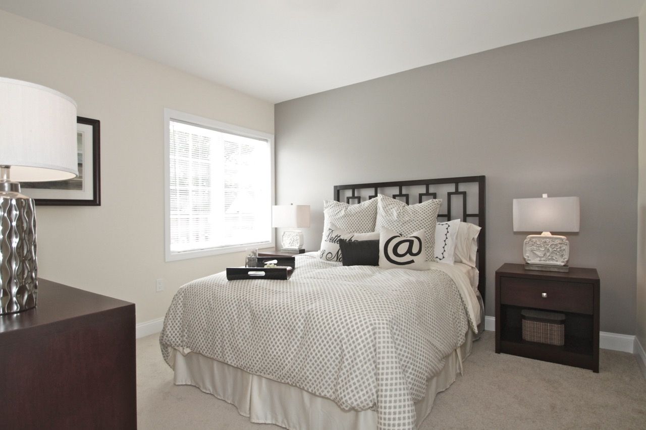 Bedroom in a modern apartment with a queen bed, two nightstands, and a large window.