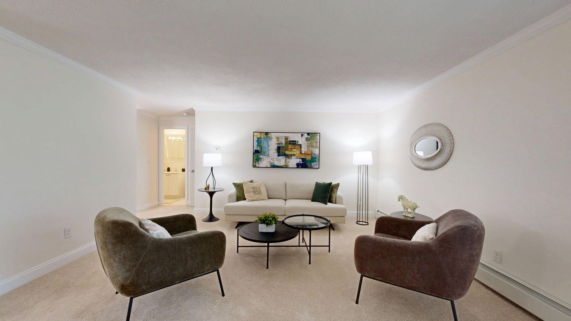 Bright modern living room with white sofa, two chairs, coffee table, floor lamp, and wall art