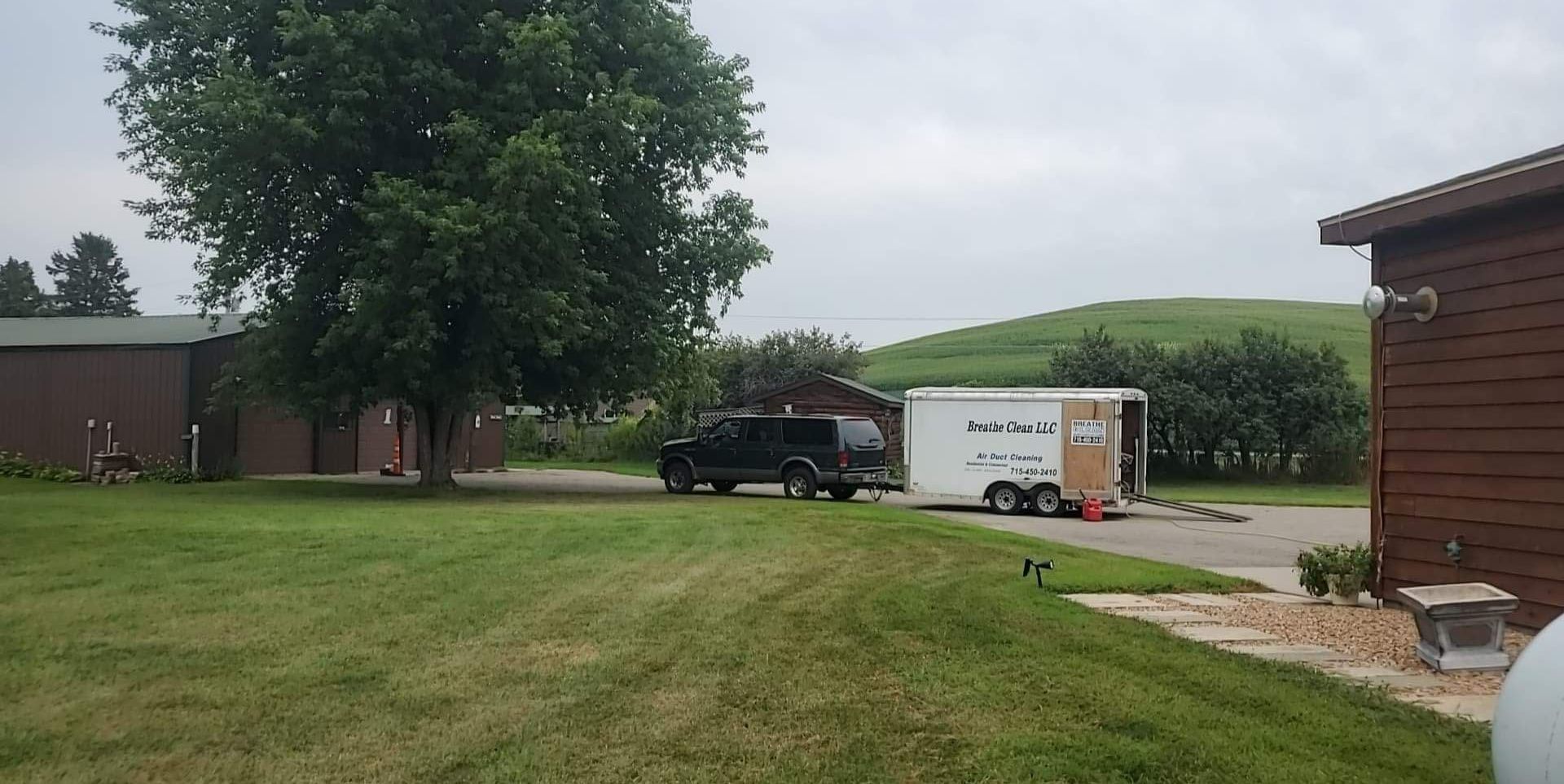 A moving truck is parked on the side of the road next to a house.