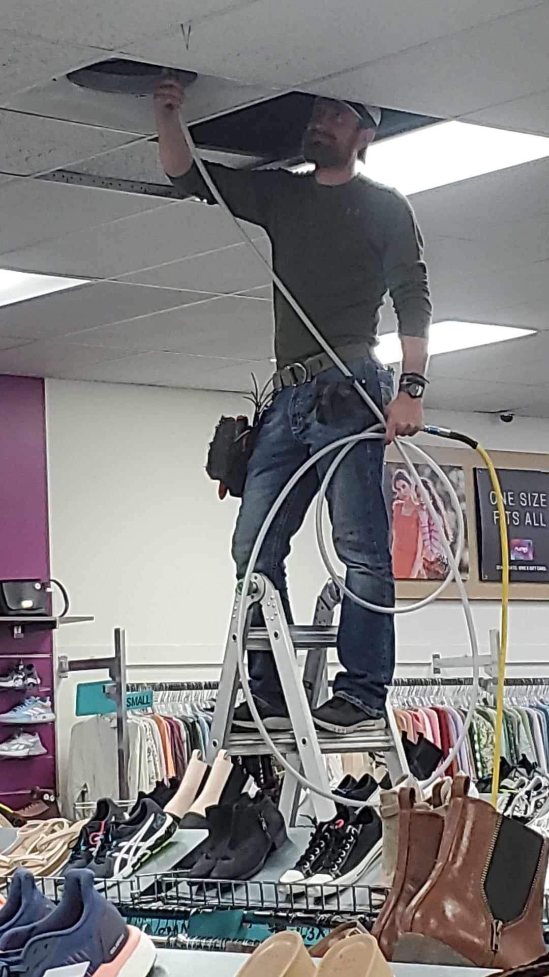 A man is standing on a ladder in a store.