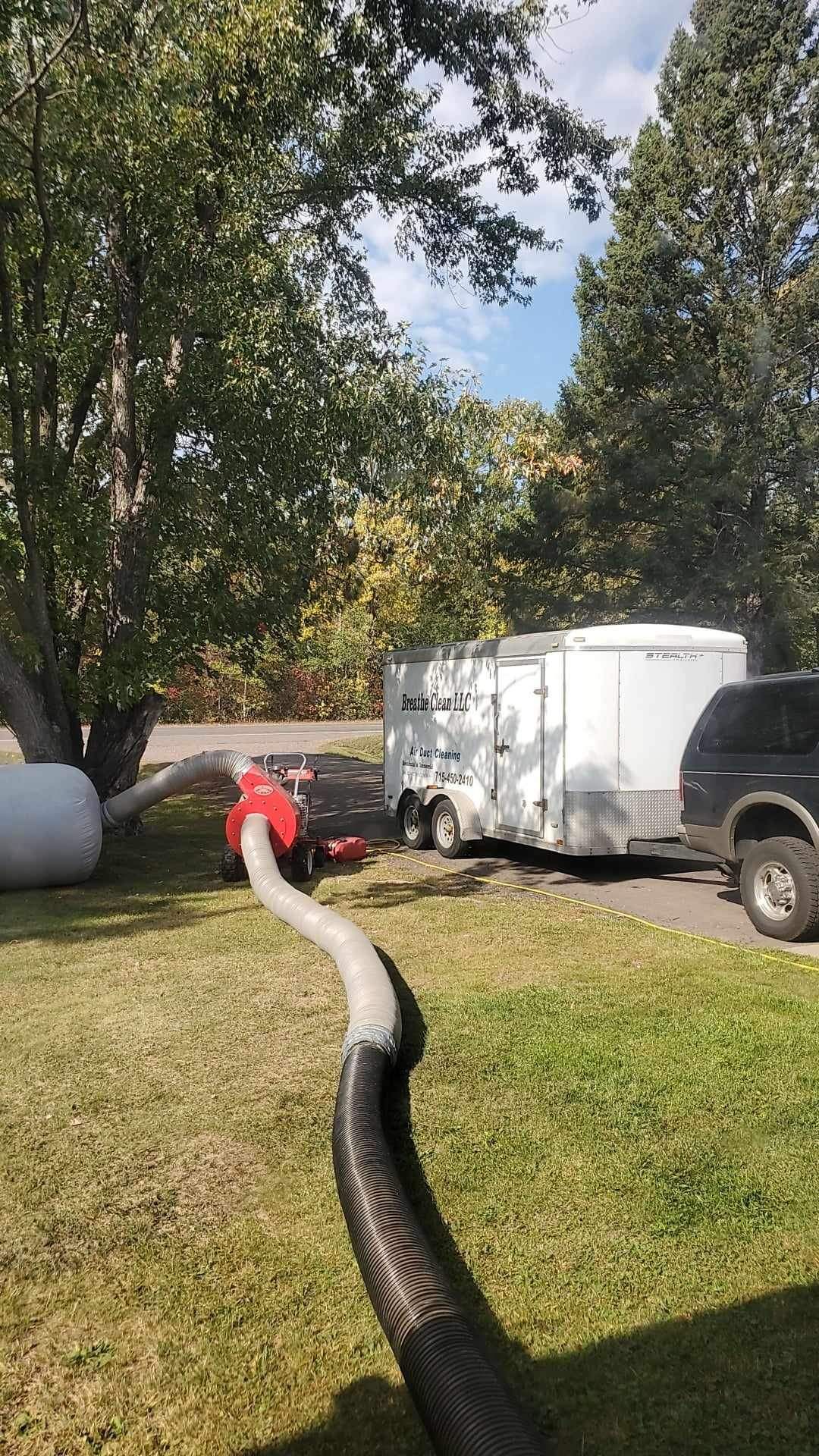 A hose is connected to a trailer in a yard.