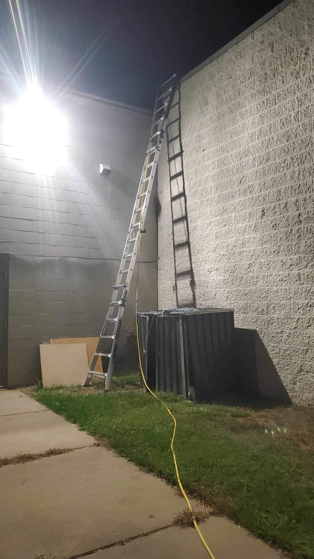 A ladder is leaning against the side of a building at night.