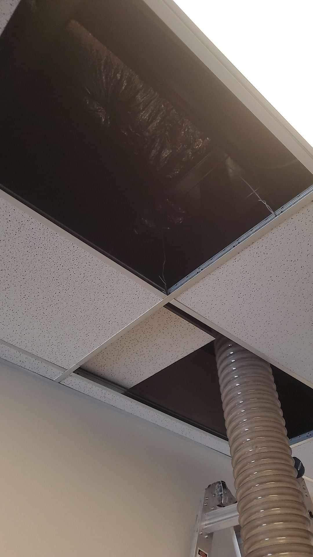 A ceiling with a hole in it and a hose coming out of it.