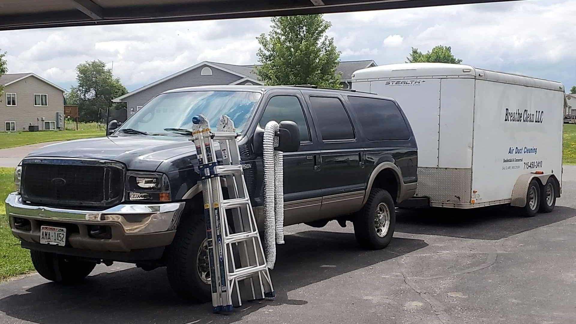 A black truck is parked next to a white trailer.