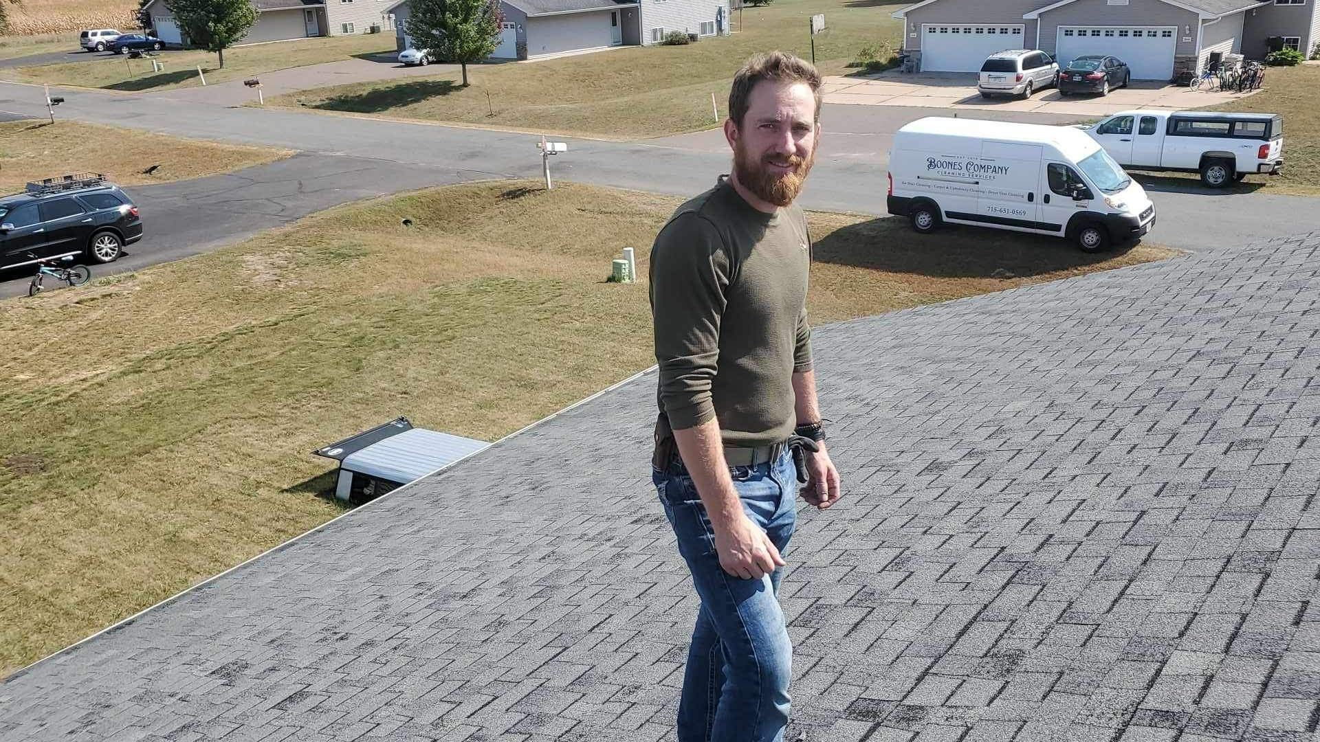A man is standing on a sidewalk next to a road.