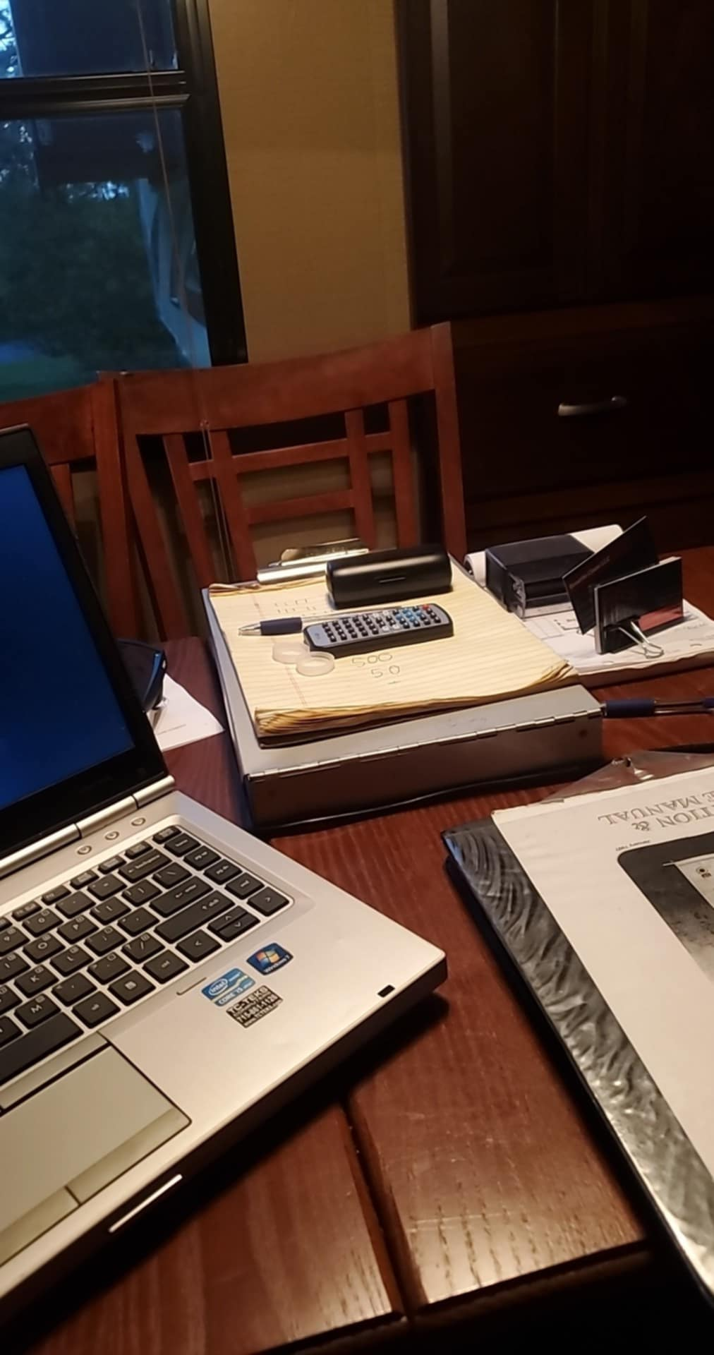 A laptop is sitting on a wooden table next to a book