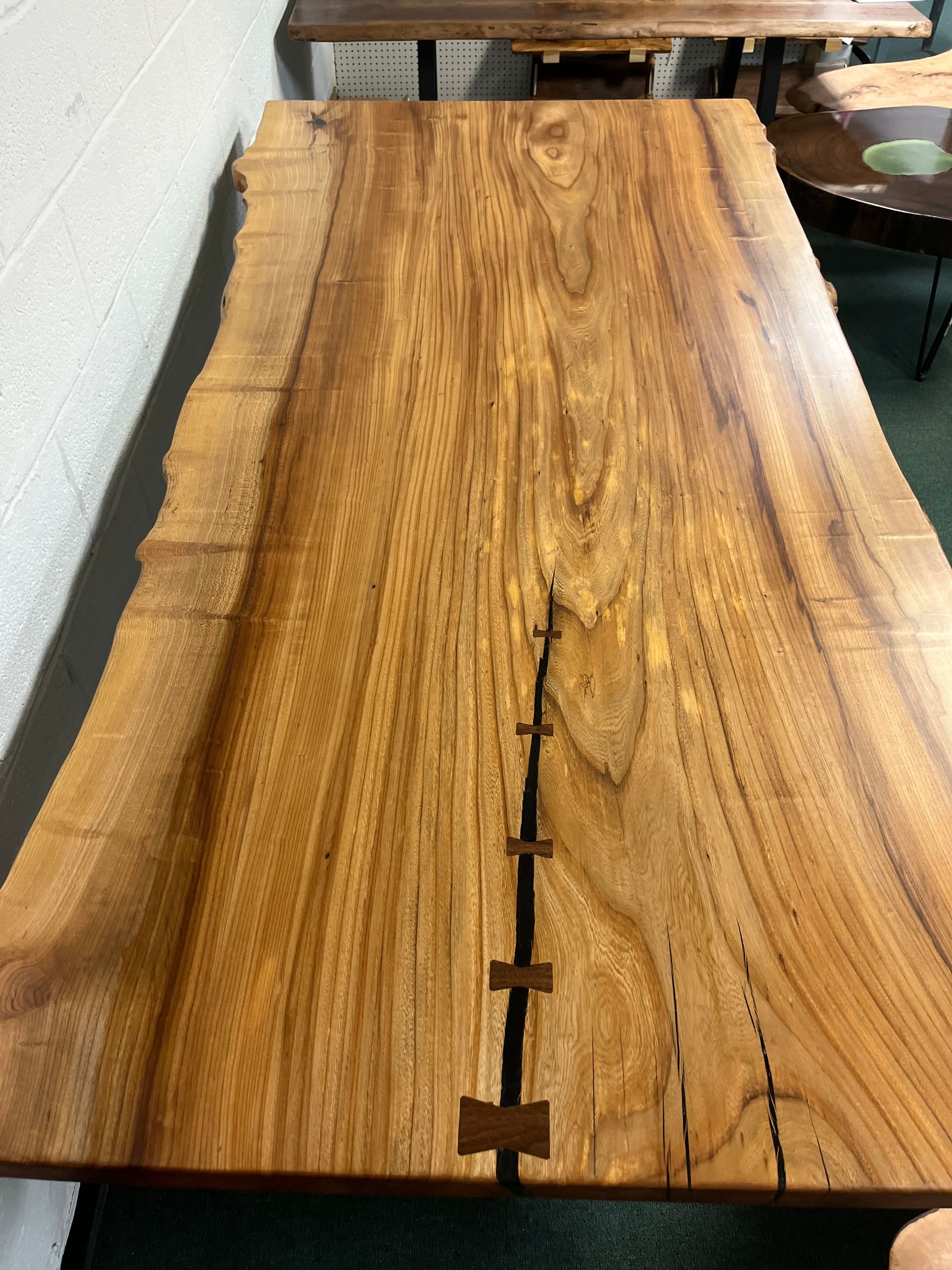 a wooden table with a black base is sitting on a tiled floor .