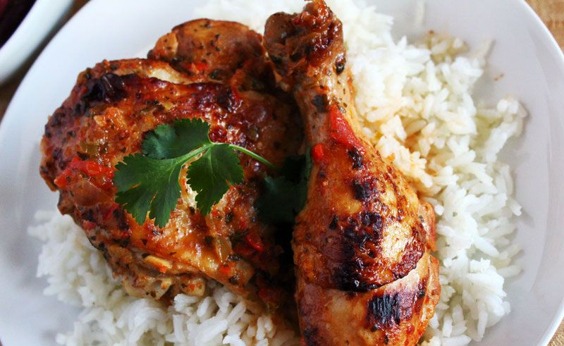Roasted chicken and rice on a white plate, garnished with cilantro.