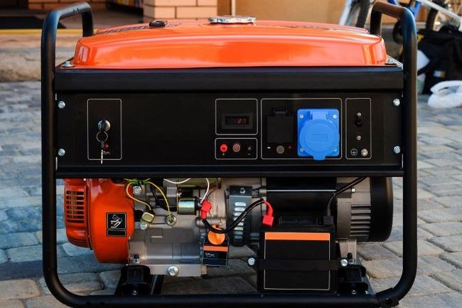 close-up of an orange portable generator showing its control panel, outlets, and engine.