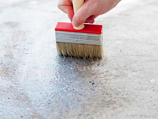 A Person Is Using A Brush To Paint A Concrete Surface  — River2Coast Concreting in Boambee, NSW