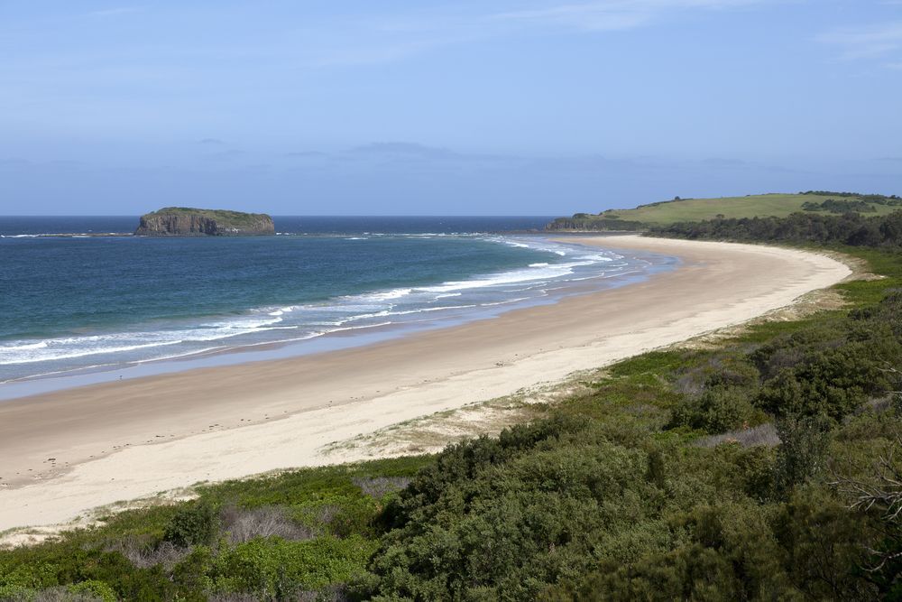 A Long Beach With A Small Island In The Distance — River2Coast Concreting in Boambee, NSW