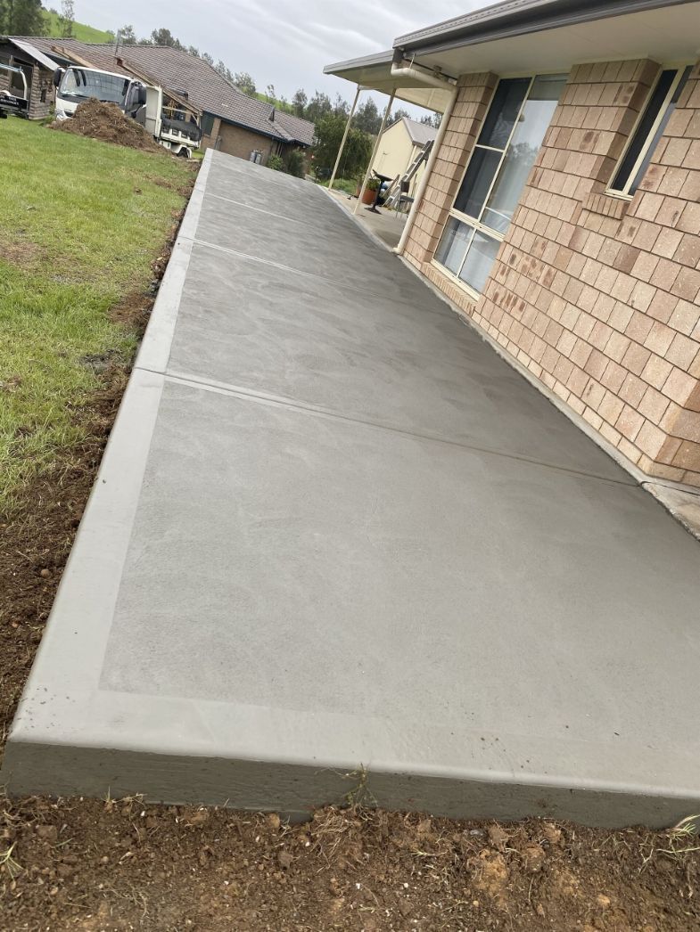 A Concrete Walkway Is Being Built In Front Of A Brick House — River2Coast Concreting in Boambee, NSW