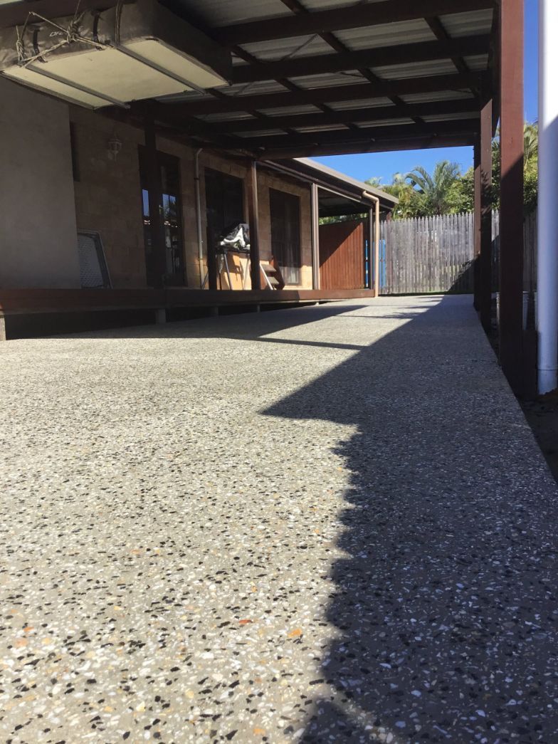 A Concrete Driveway Leading To A House With A Carport — River2Coast Concreting in Boambee, NSW