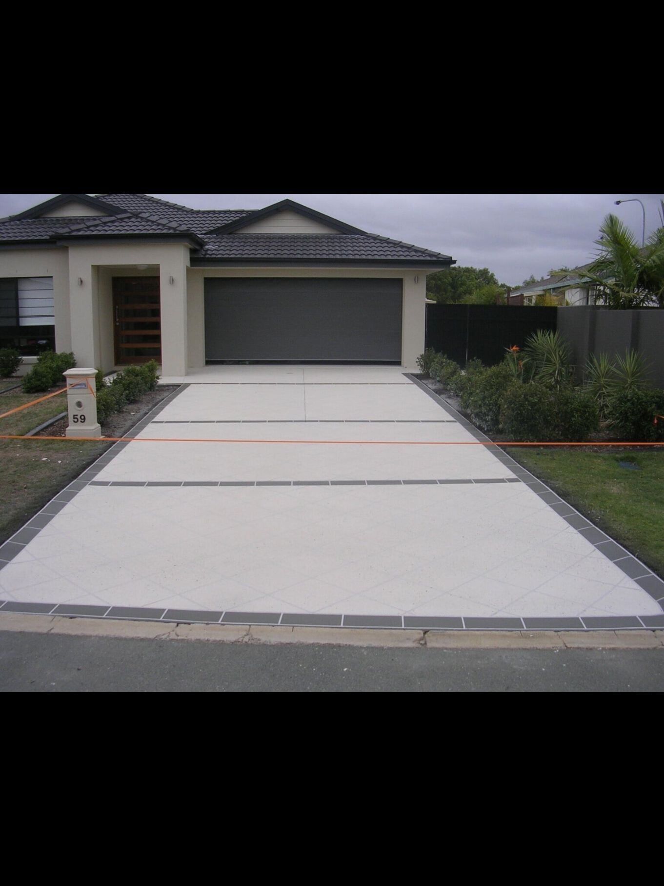 A Driveway Leading To A House With A Garage Door — River2Coast Concreting in Boambee, NSW