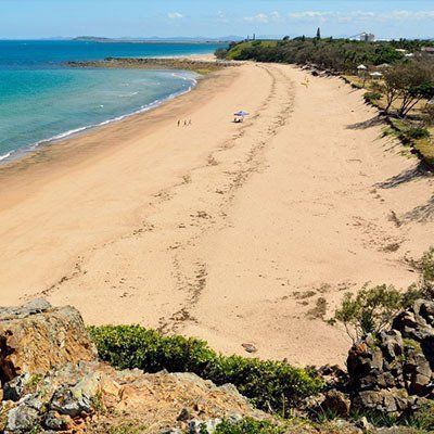 A View Of A Beach From A Cliff Overlooking The Ocean — River2Coast Concreting in Boambee, NSW