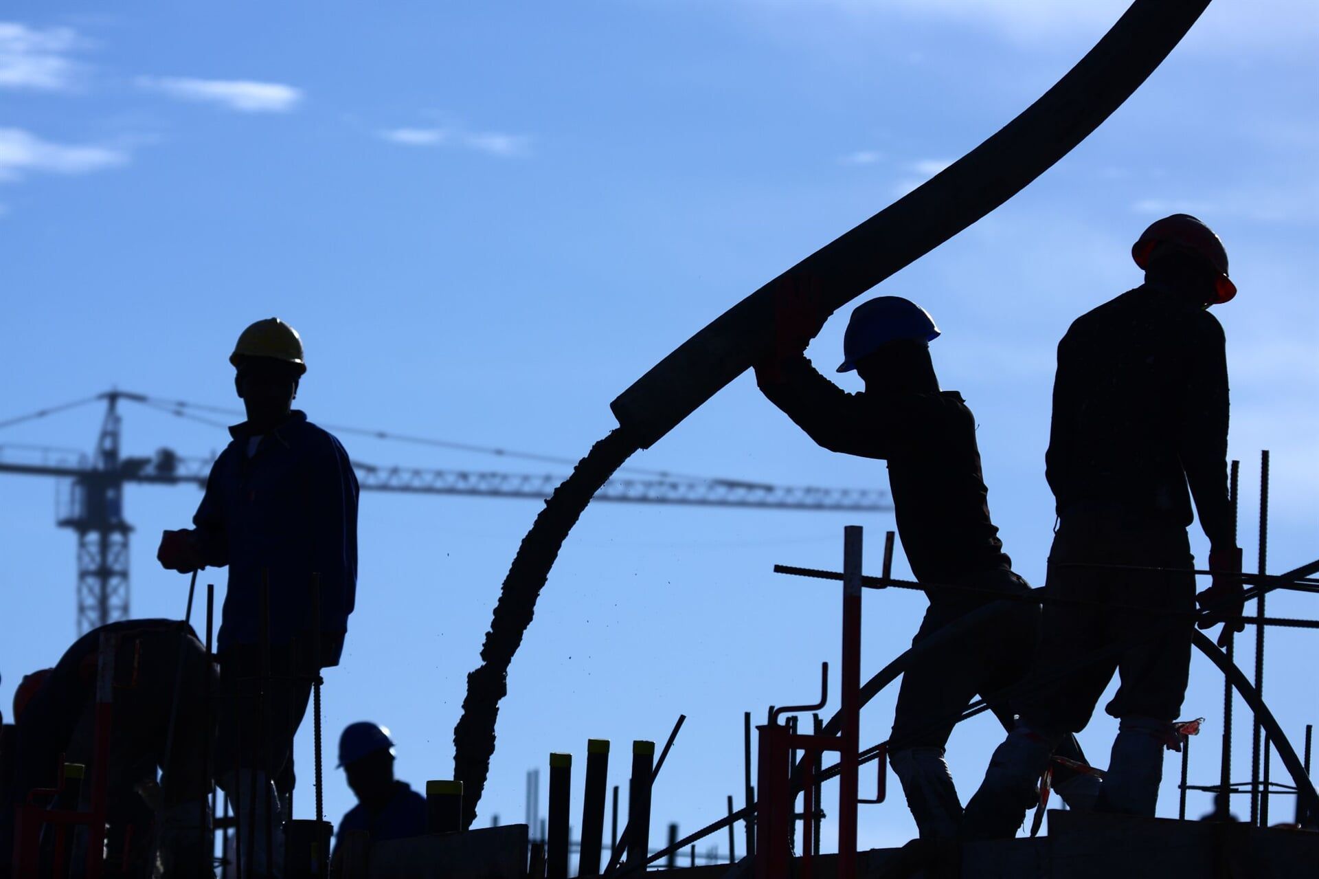 A Group Of Construction Workers Are Silhouetted Against A Blue Sky — River2Coast Concreting in Boambee, NSW