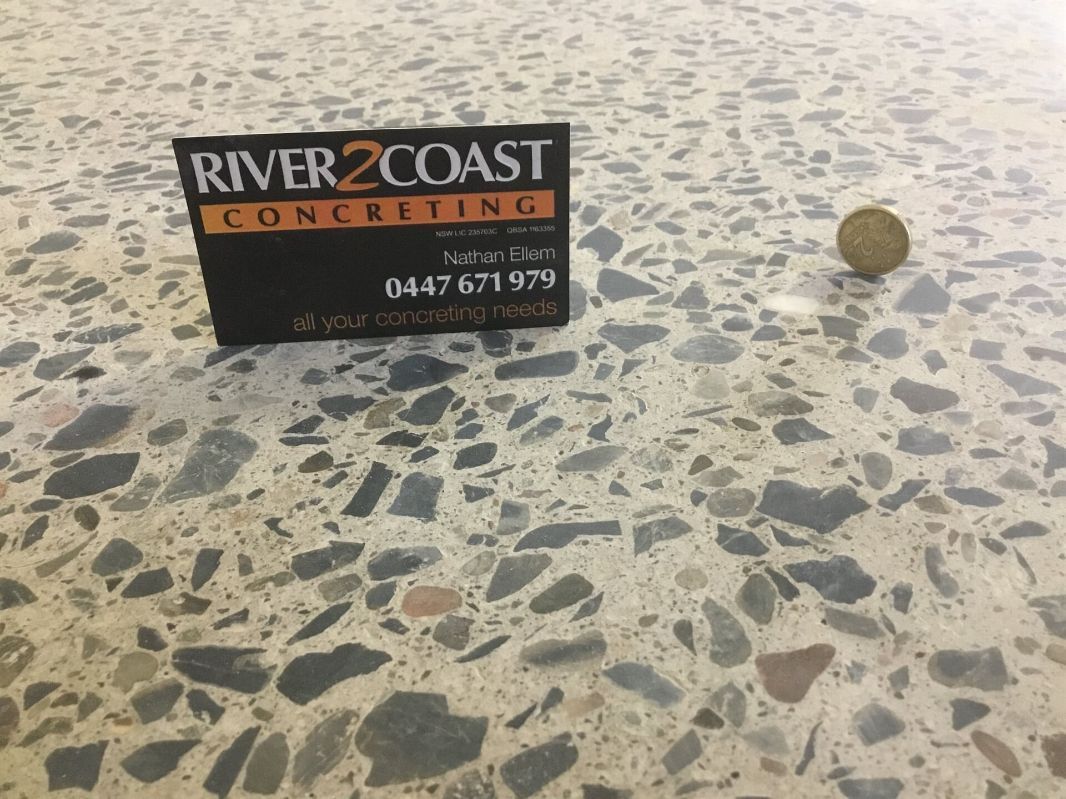 A River Coast Concrete Sign Is Sitting On A Concrete Floor  — River2Coast Concreting in Boambee, NSW