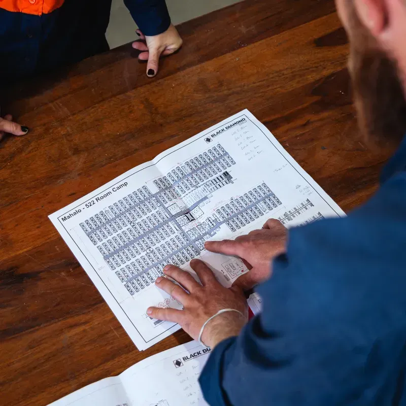 A man and a woman are standing at a table looking at a piece of paper with a technology plan on it.
