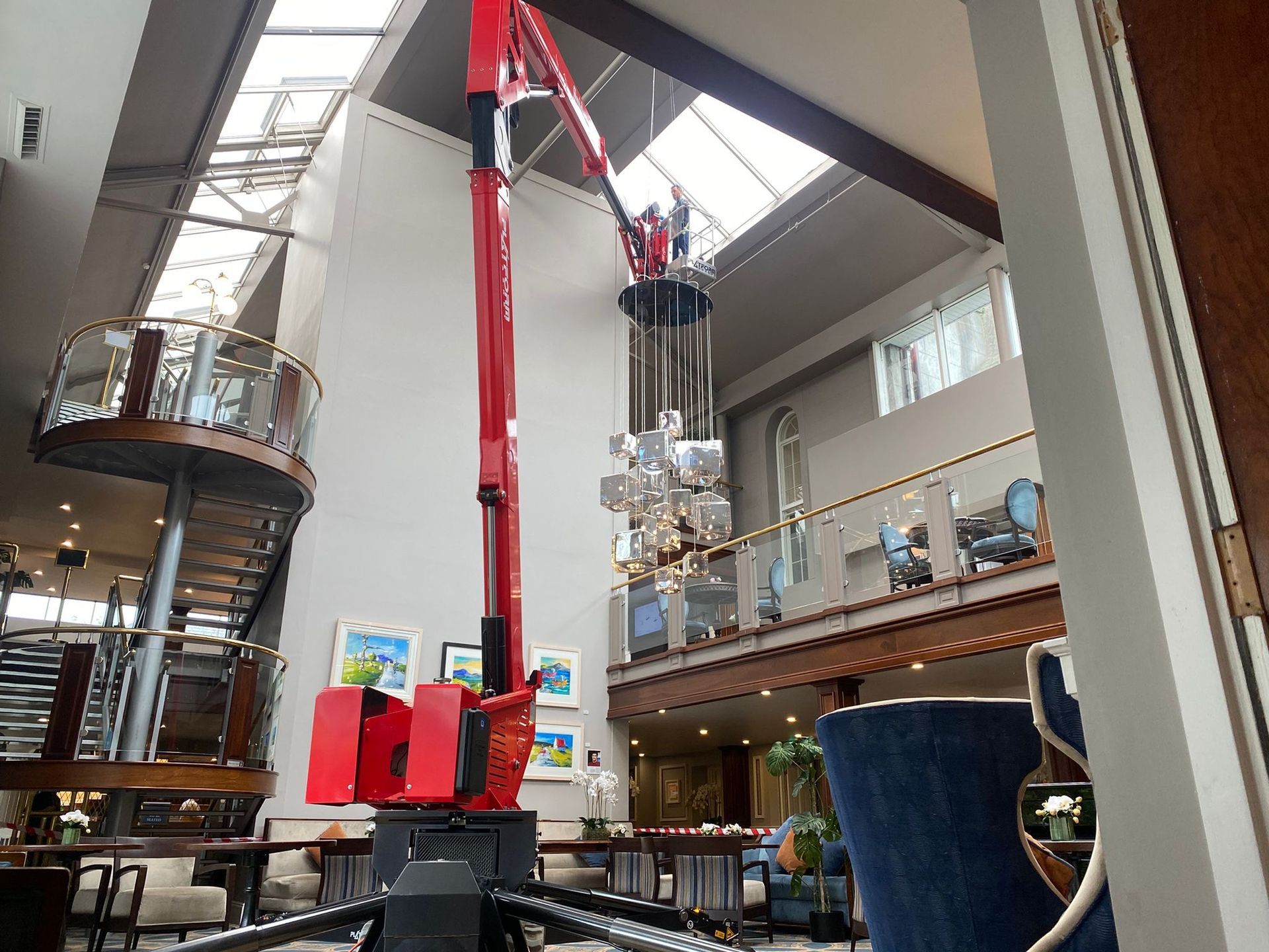 Indoor climbing gym with red wall-mounted equipment and a suspended person in a harness
