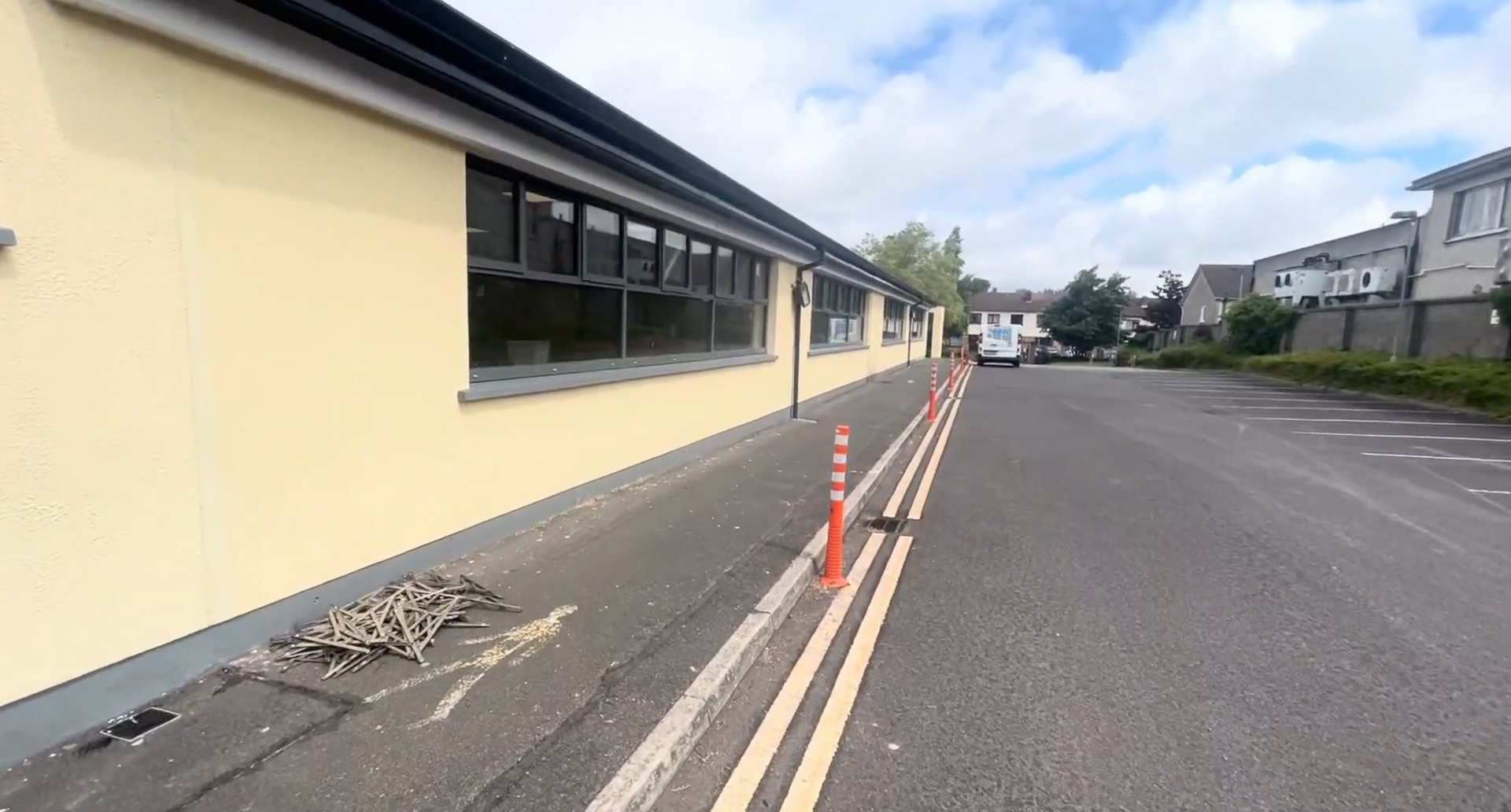Yellow building beside a roadside with orange cones and a clear sky
