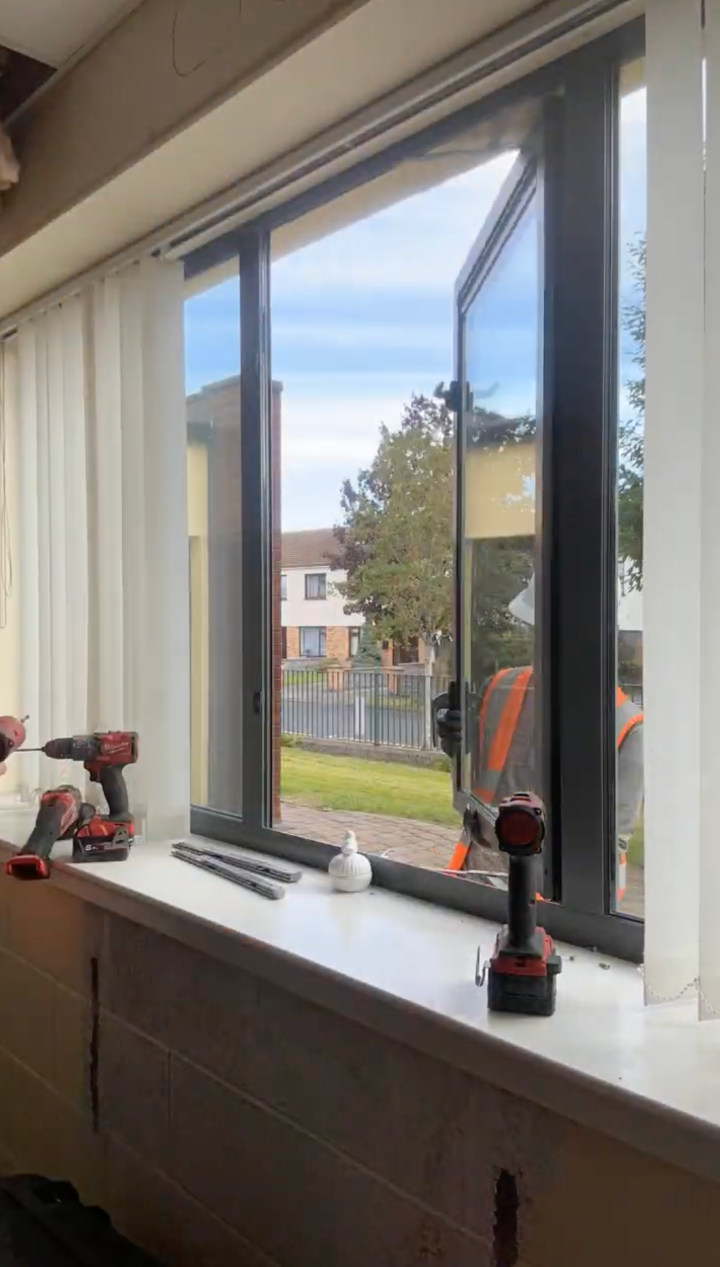 Kitchen window ledge with trophies, overlooking a suburban street and trees