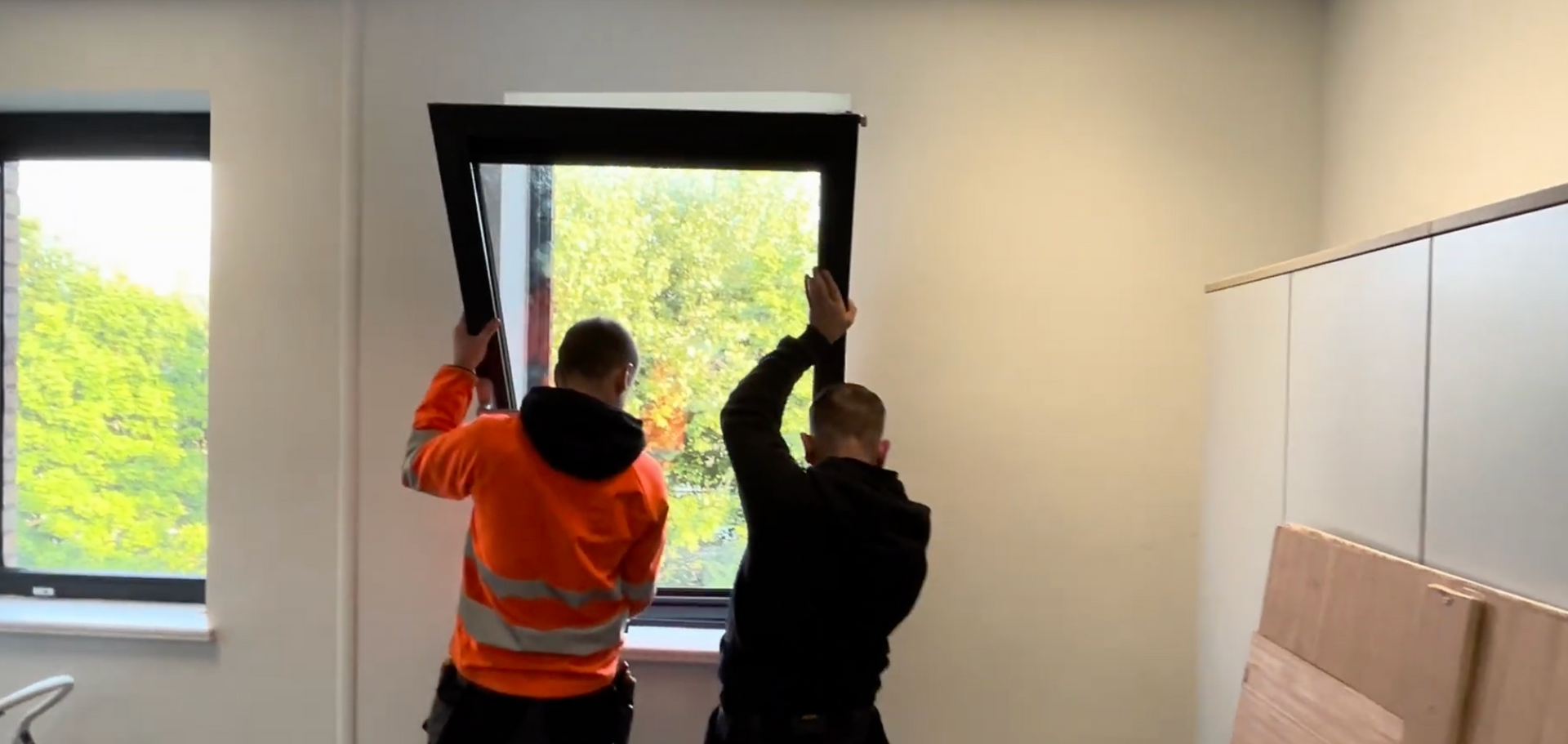 Utility truck lift basket raising workers to a window on a brick building wall