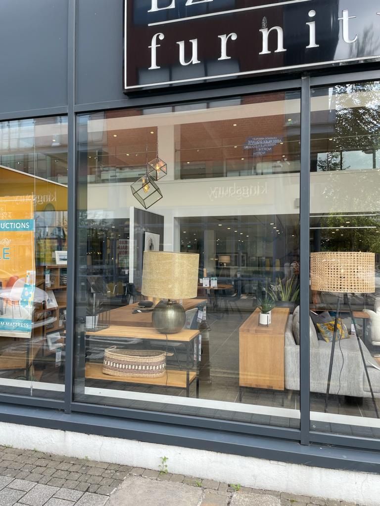 Furniture store window display with lamps, chairs, and decor behind glass storefront