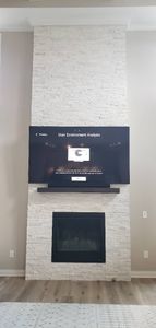 A living room with a fireplace and a flat screen tv mounted on the wall.
