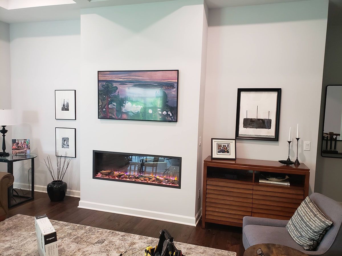 A living room with a fireplace and a flat screen tv on the wall.