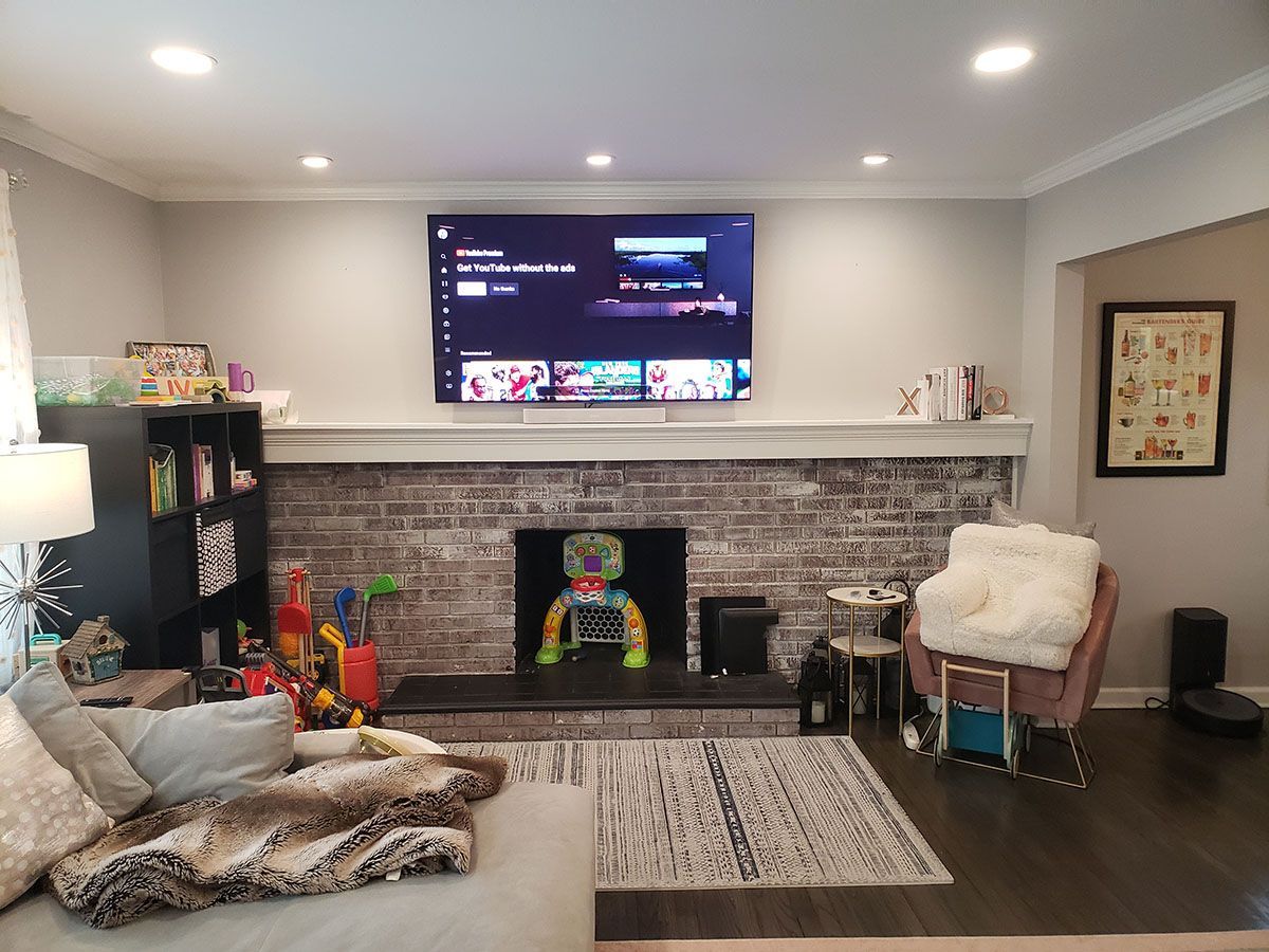 A living room with a fireplace and a flat screen tv on the wall.