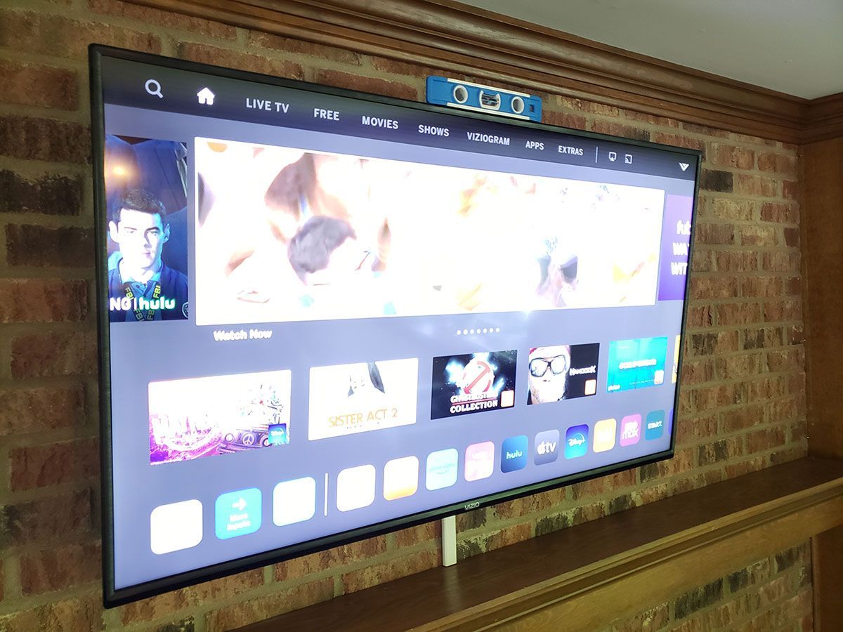 A flat screen tv is hanging on a brick wall.