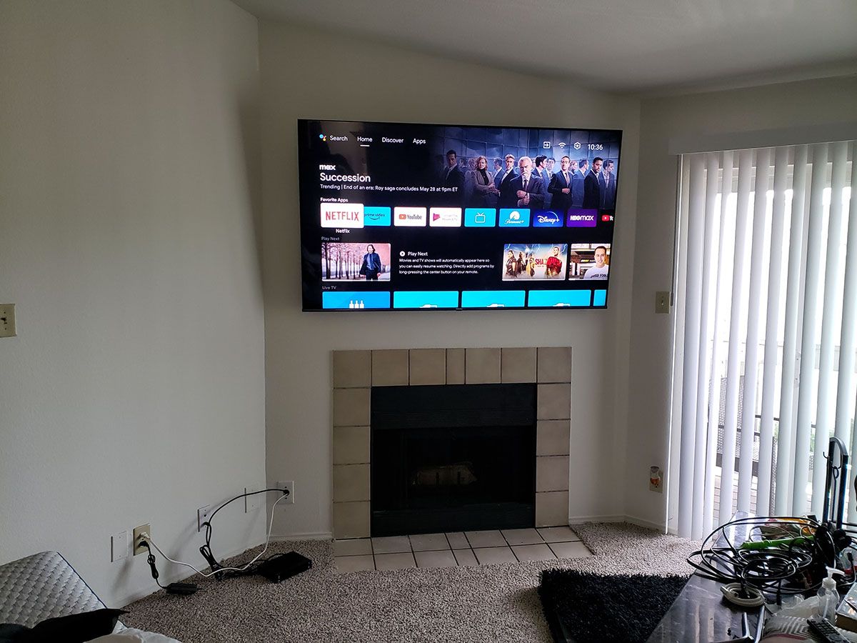 A living room with a fireplace and a flat screen tv mounted on the wall.