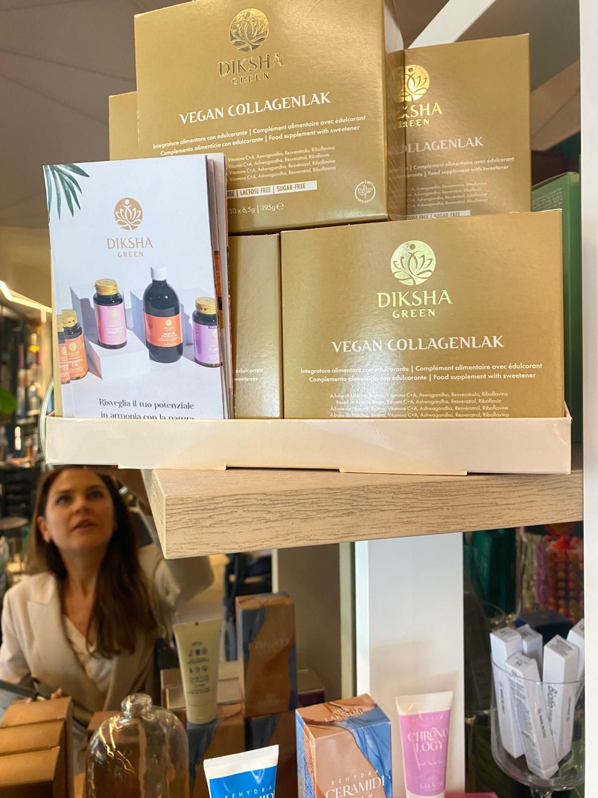 Esposizione di confezioni regalo e flaconi per prodotti per capelli OUIA su uno scaffale di un negozio, con una donna in basso.