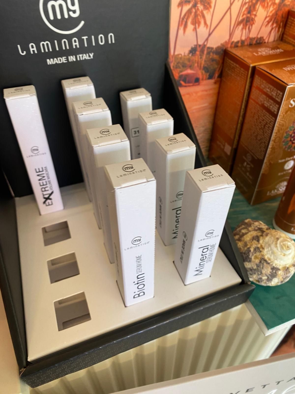 Espositore per prodotti laminato con scatole bianche e sagome di campioni su un bancone, con un cartello nero alle spalle.