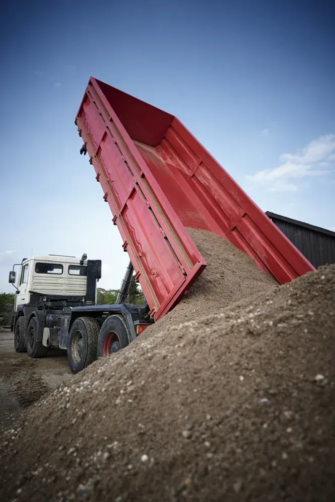 Dump truck unloading red trailer bed into a dirt pile — Rainman Domestic Water In Moore Park, QLD